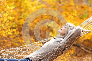 Relaxed woman lying on hammock in autumn forest