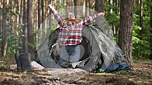 Relaxed woman opening unzipping camp tent stretching in the morning in forest with dog. Wide shot portrait of satisfied