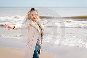 Relaxed woman,outstretched hands, enjoying spring sun, on a beautiful beach. Young lady feeling free, relaxed and happy