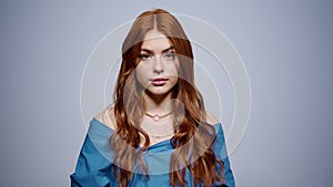 Relaxed woman posing on gray background. Redhead girl looking camera in studio