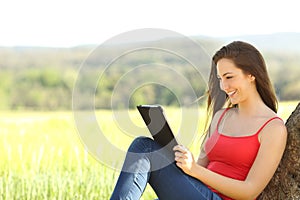 Relaxed woman reading an ebook in the country photo