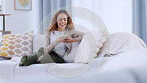 A relaxed woman reading and replying to a funny text on a phone. A lady playing an online mobile game on a sofa. Closeup