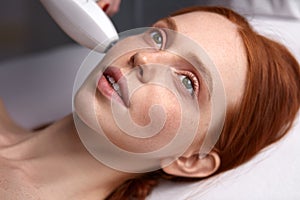 Relaxed woman receiving facial treatment by professional dermatologist