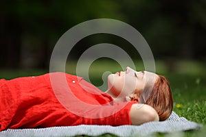 Relaxed woman in red resting on the grass in a forest