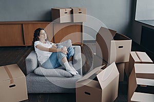 Relaxed woman rests in armchair during packing things for moving at new home. Mortgage advertising