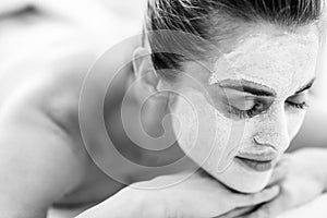 Relaxed woman with revitalising mask on face laying on mas