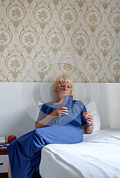 Relaxed woman sitting on the bed in the hotel, holding a smartphone or shop online to check mobile application or social