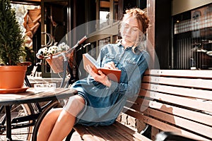 Relaxed woman sitting on bench and writing in notebook