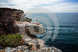 Relaxed woman sitting on coastal headland looking out to ocean