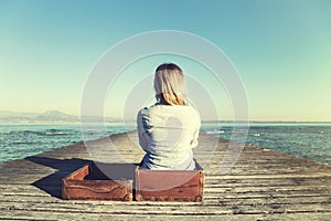 Relaxed woman sitting in her big suitcase after a long journey