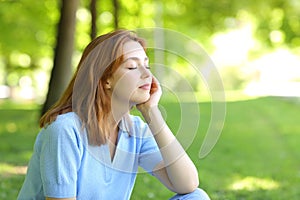 Relaxed woman sitting in a park with closed eyes