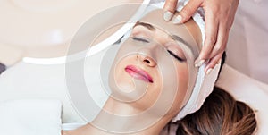 Relaxed woman smiling under the benefits of anti-aging facial ma