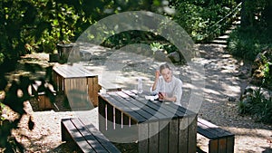 Relaxed woman speaking video meeting by cell phone sitting table picnic spot.