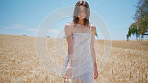 Relaxed woman strolling sunlight farmland. Serene lady touching wheat at harvest