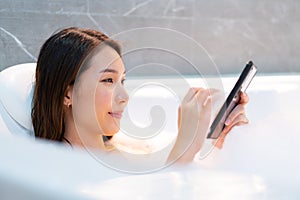 Relaxed woman touching skin with foam in bathtub