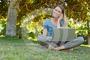 Relaxed woman using laptop and mobile phone at park