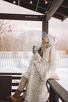 Relaxed woman in warm winter clothes plaid drinking hot cocoa coffee tea outdoor winter nature