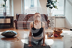 Relaxed woman works out doing yoga in bhujangasana pose in room