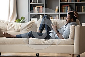 Relaxed young african ethnicity man using mobile phone.