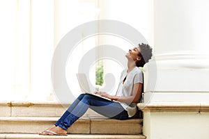 Relaxed young african woman sitting outside with her laptop