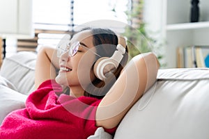 Relaxed young Asian woman enjoying rest on comfortable sofa