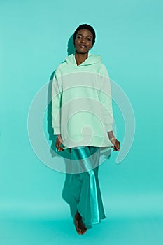 Relaxed young black woman in oversized sweatshirt and satin long dress