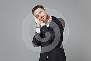 Relaxed young business man in classic black suit shirt posing  on grey wall background. Achievement career