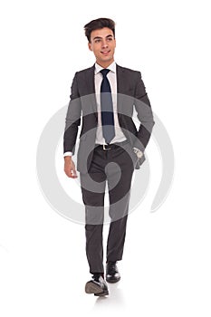 Relaxed young business man is walking with hand in pocket