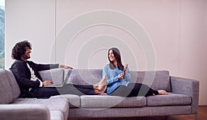 Relaxed Young Couple At Home Sitting On Sofa Using Digital Tablet And Laptop Computer