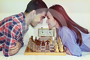 Relaxed young couple playing chess at home lying on sofa. won - Friendship.