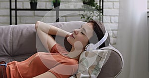 Relaxed young european girl listening to calm music in headphones.