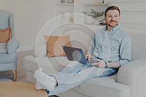 Relaxed young man surfing web while sitting on couch