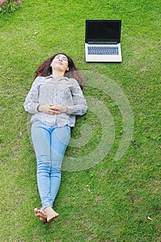 Relaxed young person (teenage girl) lying in grass