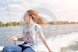 Relaxed young woman with closed eyes of pleasure sitting on sailboat, enjoying mild sunlight, sea or river cruise, summer vacation