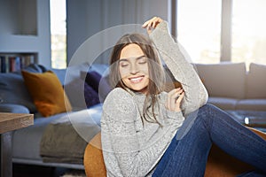 Relaxed young woman daydreaming in armchair at home