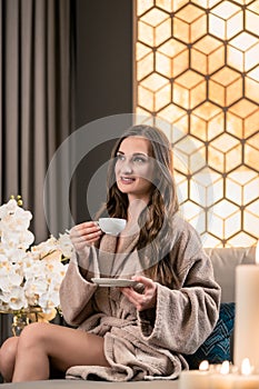 Relaxed young woman drinking herbal tea before spa treatment