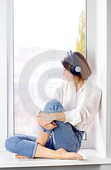 Relaxed young woman enjoying listening to music in wireless earphones at home, stress free meditation concept