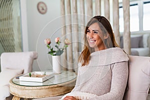 Relaxed young woman enjoying morrning sitting on a comfortable couch staring thoughtfully ahead. Enjoying time at home