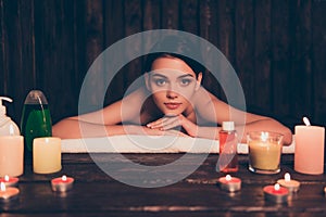 Relaxed young woman laying in spa salon with candles and lotions