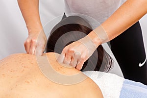 Relaxed young woman lying face down on massage table enjoying therapeutic body massage by professional masseur in spa or wellness