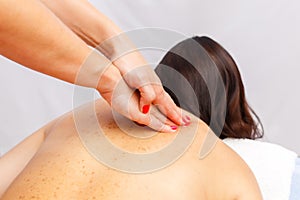 Relaxed young woman lying face down on massage table enjoying therapeutic body massage by professional masseur in spa or wellness