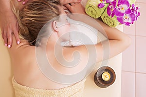 Relaxed young woman on massage table receiving beauty treatment at day spa