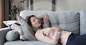 Relaxed young woman napping lying on comfortable sofa at home