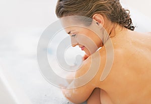 Relaxed young woman sitting in bathtub. rear view