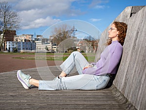 Relaxed Young Woman Sitting in Urban Park on Sunny Day