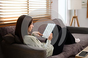Relaxed young woman surfing internet on digital tablet in living room