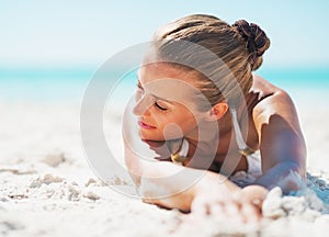 Relaxed young woman in swimsuit laying on sandy beach