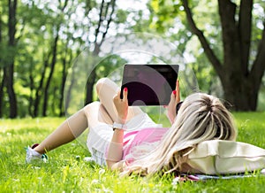 Relaxed young woman using tablet computer outdoors