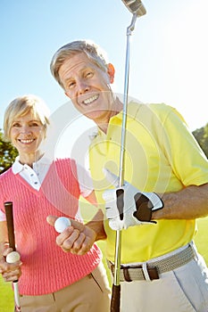 Relaxing activities for the elderly. Elderly couple holding their golf clubs and balls on the green.