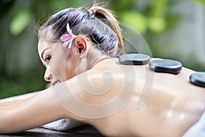 Relaxing asian woman enjoying hot stone massage